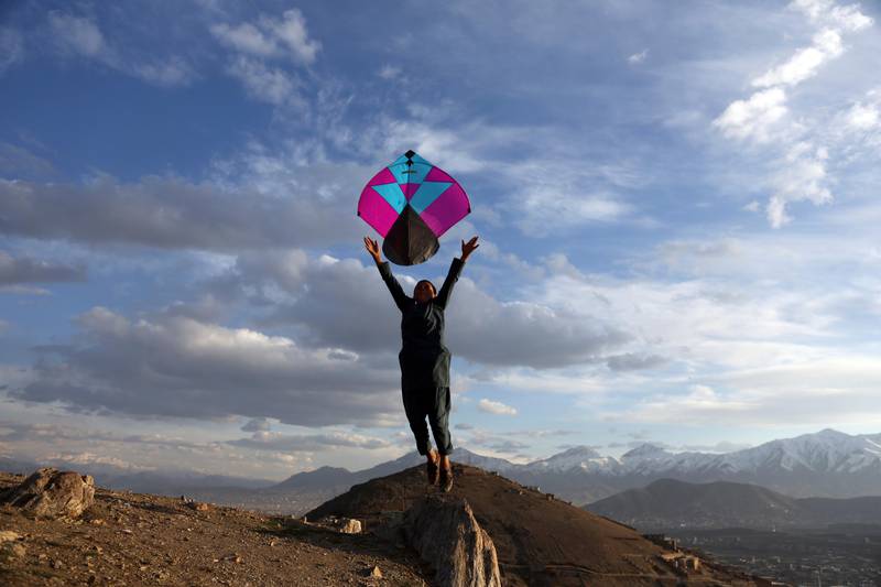 An Afghan boy launches a kite for his friend on hilltop on the the outskirts of Kabul, Sunday, March, 4, 2018. (AP Photo/Rahmat Gul)