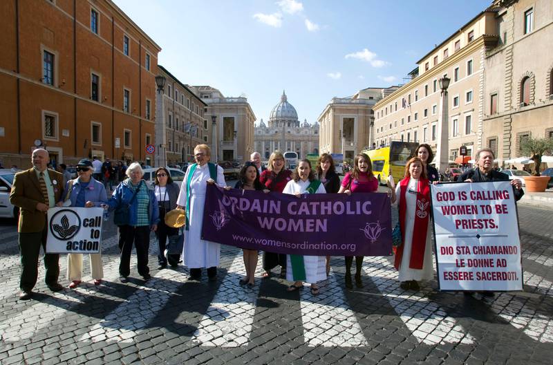 Members of the Women's Ordination Conference group stage a protest in front of St. Peter's Basilica, in Rome, Monday, Oct. 17, 2011. A U.S. Catholic priest who supports ordination for women has been detained by police after marching to the Vatican to press the Holy See to lift its ban on women priests. The Rev. Roy Bourgeois and two supporters were taken away Monday in a police car after their group marched down the main boulevard leading to the Vatican and chanted outside St. Peter's Square "What do we want? Women priests!". Rev. Roy Bourgeois is seen holding a banner at right.  (AP Photo/Andrew Medichini)