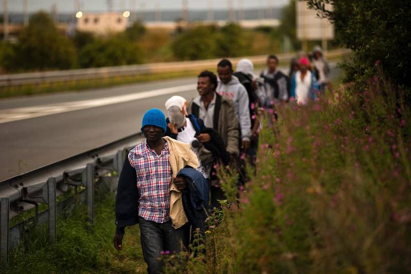 Flyktninger går langs en motorvei i Nord-Frankrike. Bildet er fra i sommer.