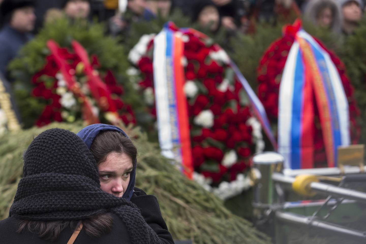 A woman comforts Boris Nemtsov's daughter Zhanna Nemtsova, second left, at the grave of Boris Nemtsov after a burial ceremony at Troekurovskoye cemetery in Moscow, Russia, Tuesday, March 3, 2015.  One by one, thousands of mourners and dignitaries filed past the white-lined coffin of slain Kremlin critic Boris Nemtsov on Tuesday, many offering flowers as they paid their last respects to one of the most prominent figures of Russia's beleaguered opposition. (AP Photo/Denis Tyrin)
