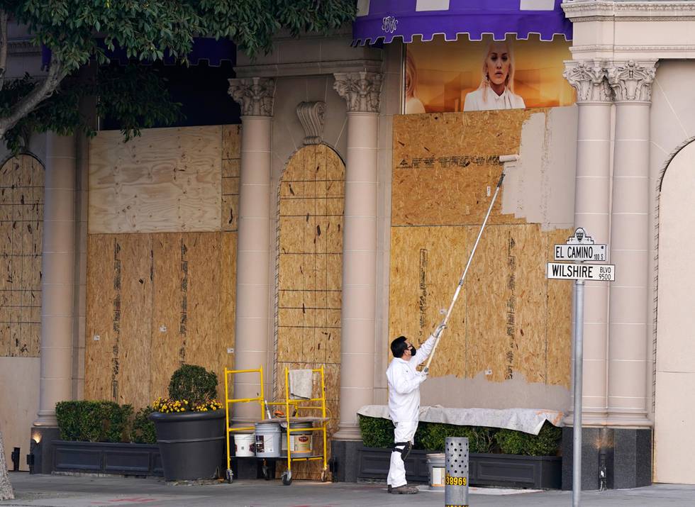 A laborer paints a boarded up window at the Beverly Wilshire Hotel, Friday, Oct. 30, 2020, in Beverly Hills, Calif. Retailers, including Nordstrom, Tiffany and Saks Fifth Avenue, are boarding up their windows and planning to add extra security personnel in some of their locations ahead of the contentious presidential election on Tuesday. (AP Photo/Chris Pizzello)