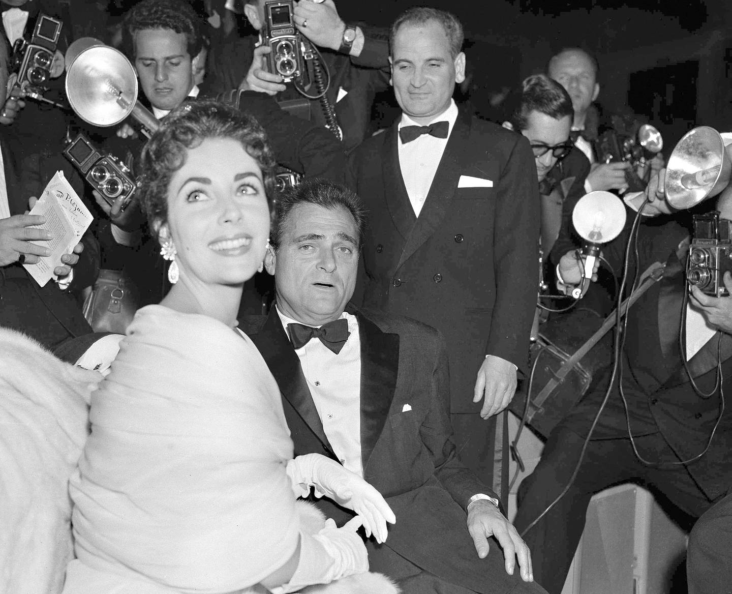 In this May 2, 1955 file photo film star Elizabeth Taylor and her husband, producer Mike Todd are surrounded by photographers at the Cannes Film Festival in Cannes. It is one of the indelible moments the Cannes Film Festival has created throughout its history, and more were likely to be made when it opened on Tuesday, May 12, 2020. This year's festival has been postponed due to the coronavirus pandemic. (AP Photo/Babout, File)
