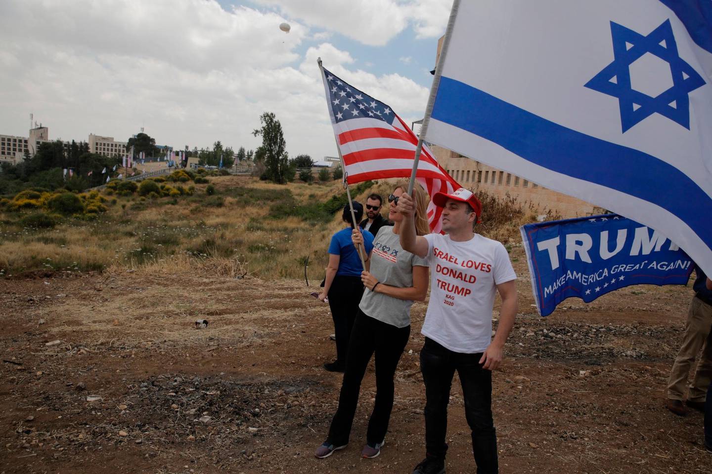Israelis hold American and Israeli flags with the new U.S. embassy in the background in Jerusalem, Monday, May 14, 2018. Israel prepared for the festive inauguration of a new U.S. Embassy in contested Jerusalem. (AP Photo/Sebastian Scheiner)