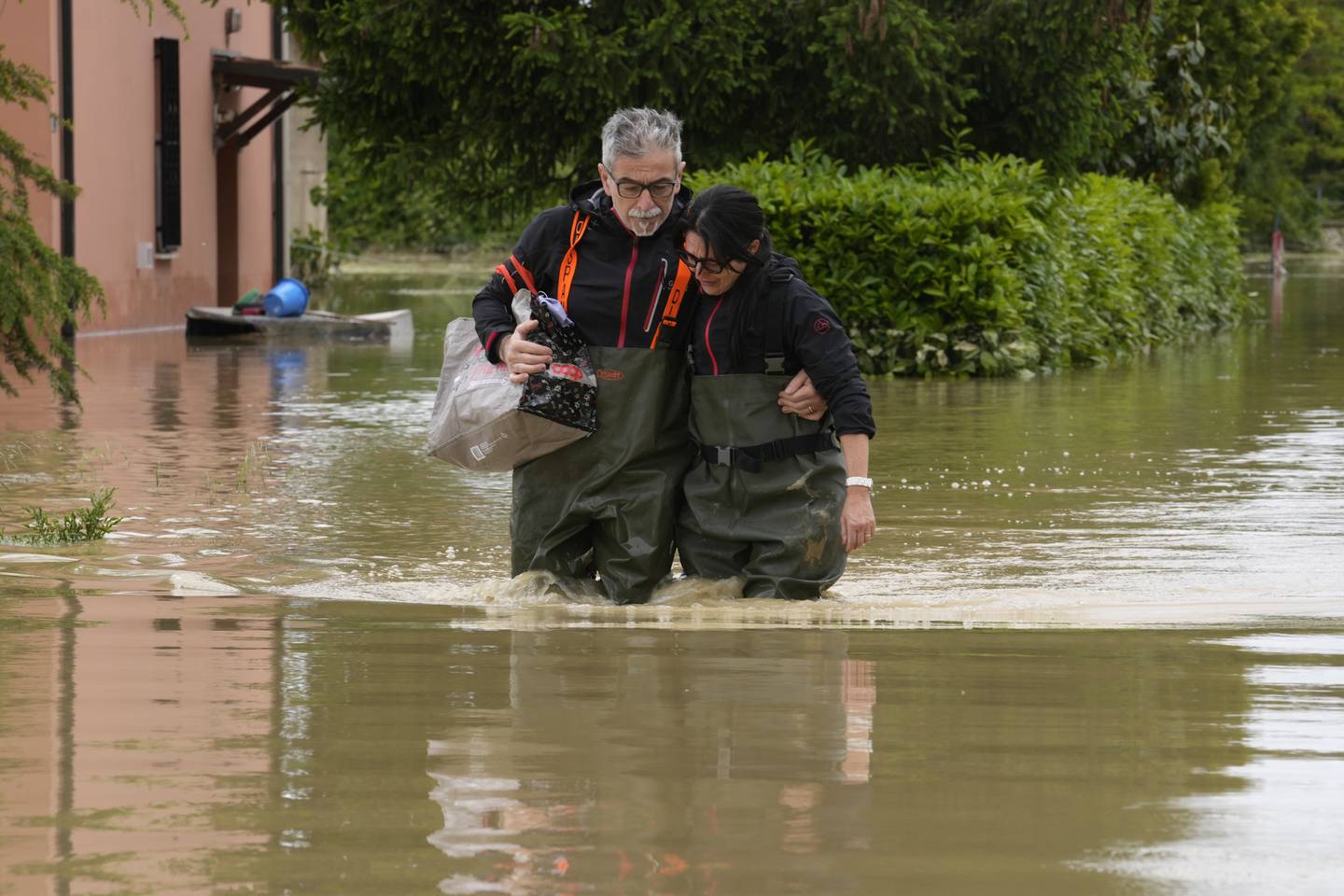 Et ektepar vader gjennom flomvannet i Lugo i Italia 18. mai. Faren for jordskred i regionen er nå spesielt høy. Foto: Luca Bruno / AP / NTB