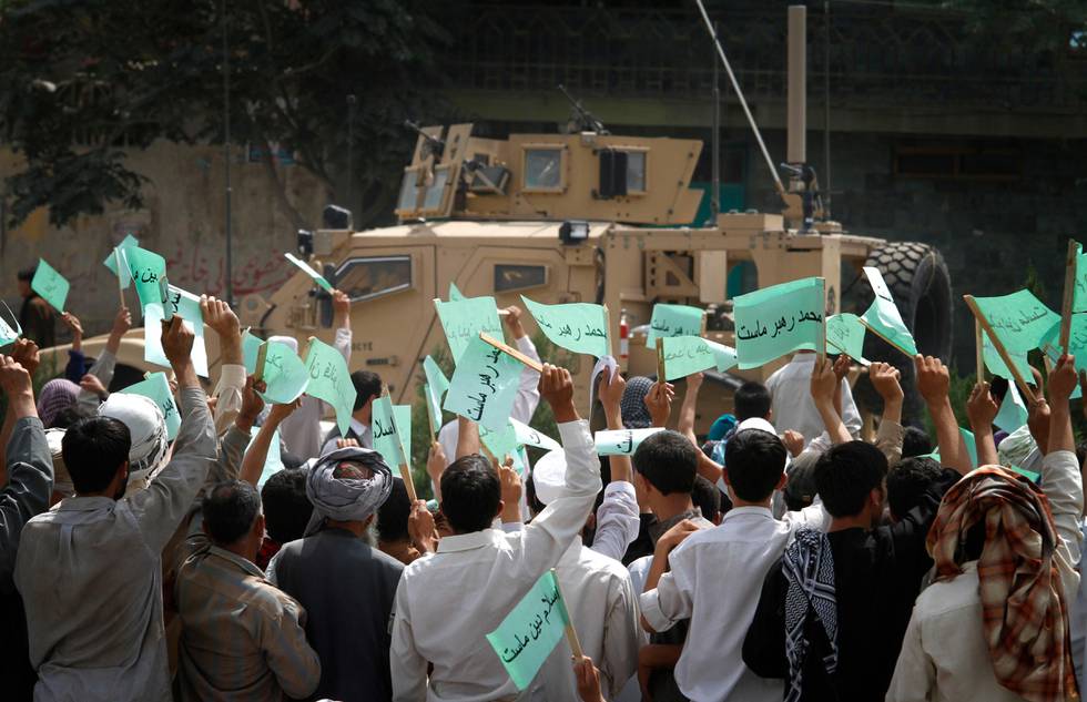 Afghans wave banners saying "Quran is our law, Islam is our religion and Mohammad is our leader" to a U.S. military convey during a demonstration against the United States, in Kabul, Afghanistan, Monday, Sept. 6, 2010. Hundreds of Afghans railed against the U.S. and called for President Barack Obama's death at a rally in the capital Monday to denounce an American church's plans to burn the Islamic holy book on 9/11. (AP Photo/Musadeq Sadeq)