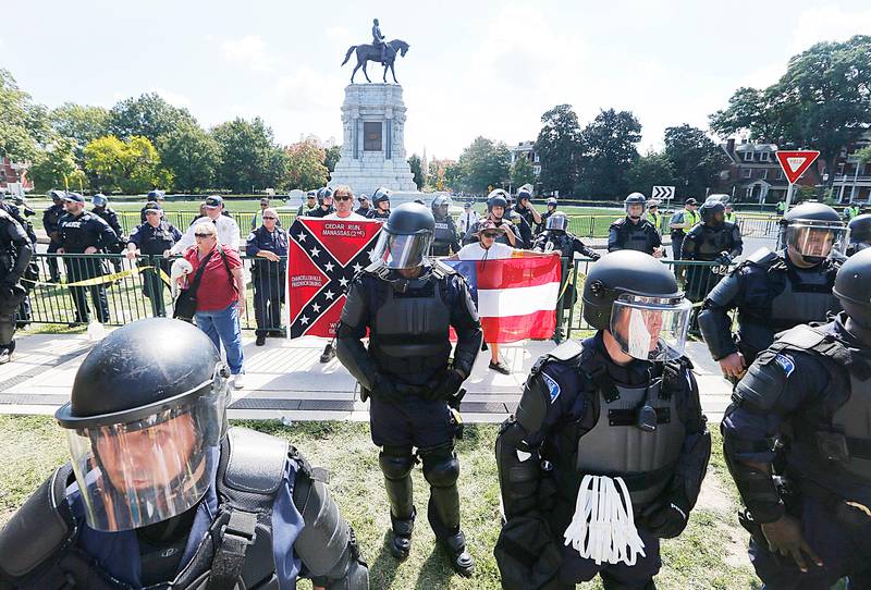 FILE - In this Sept. 16, 2017 file photo, State Police keep a handful of Confederate protesters separated from counter demonstrators in front of the statue of Confederate General Robert E. Lee on Monument Avenue in Richmond, Va. President Donald Trump on Friday, April 26, 2019 revived the debate over the legacy of Gen. Robert E. Lee when he described the Confederate military leader as "a great general, everybody knows that." The comments prompted backlash given Lee?ƒÙs role in leading the Confederate Army during the Civil War and his symbolism in current American race relations amid the fallout over 2017 racial violence in Charlottesville, Virginia, during protests over a Lee statue.  (AP Photo/Steve Helber, File)