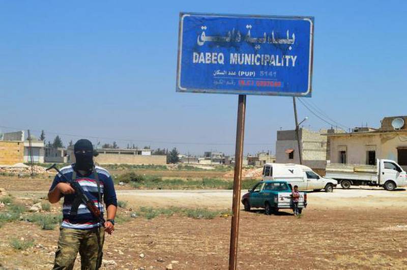 En mann poserer ved byskiltet til Dabiq i Nord-Syria. 