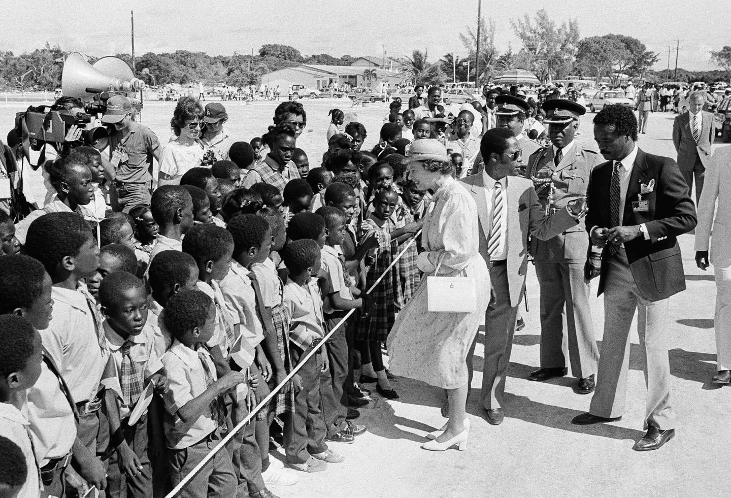 Her Majesty Queen Elizabeth II steps to the rope to meet school children of the Fresh Creek Primary School on Monday, Oct. 14, 1985 in Andros, The Bahamas.  She officially opened the newly completed sporting facility in Fresh Creek.    The Queen is on a tour of the Commonwealth Islands in the Bahamas. (AP Photo/Barry Thumma)