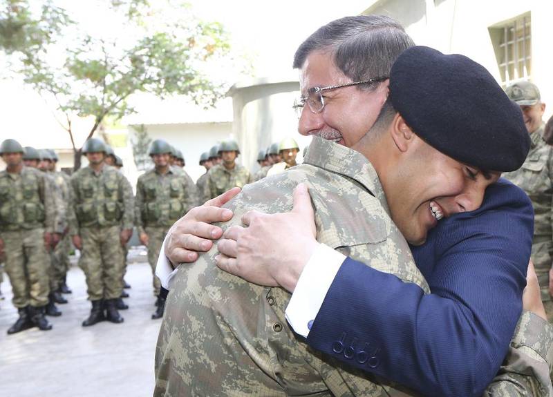 Den tyrkiske statsministeren Ahmet Davutoglu omfavner en soldat under et besøk i det syrisk-tyrkiske området 10. mai.  Foto: Hakan Goktepe via Reuters