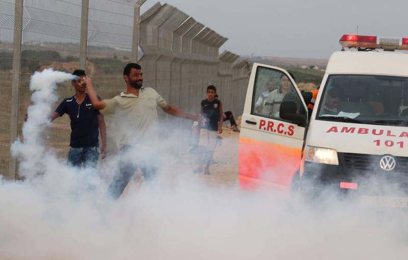 En palestinsk demonstrant kaster en tåregassbeholder tilbake mot de israleske styrkene under sammenstøt nær grensen til den sentrale Gaza-stripen 19. oktober.