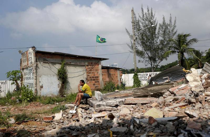 Ruiner: En av innbyggerne i Vila Autodromo, Marcio Moza, sitter på restene av huset sitt som akkurat har blitt revet ned av myndighetene. 