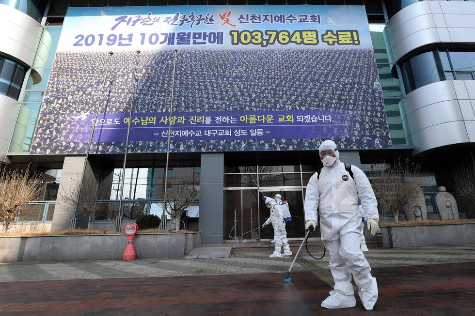 In this Thursday, Feb. 20, 2020, photo, workers wearing protective gears spray disinfectant against the new coronavirus in front of the Shincheonji church in Daegu, South Korea. South Korea on Friday, Feb. 21, declared a "special management zone" around a southeastern city where a surging viral outbreak, largely linked to a church in Daegu, threatens to overwhelm the region's health system. (Kim Jun-beom/Yonhap via AP)