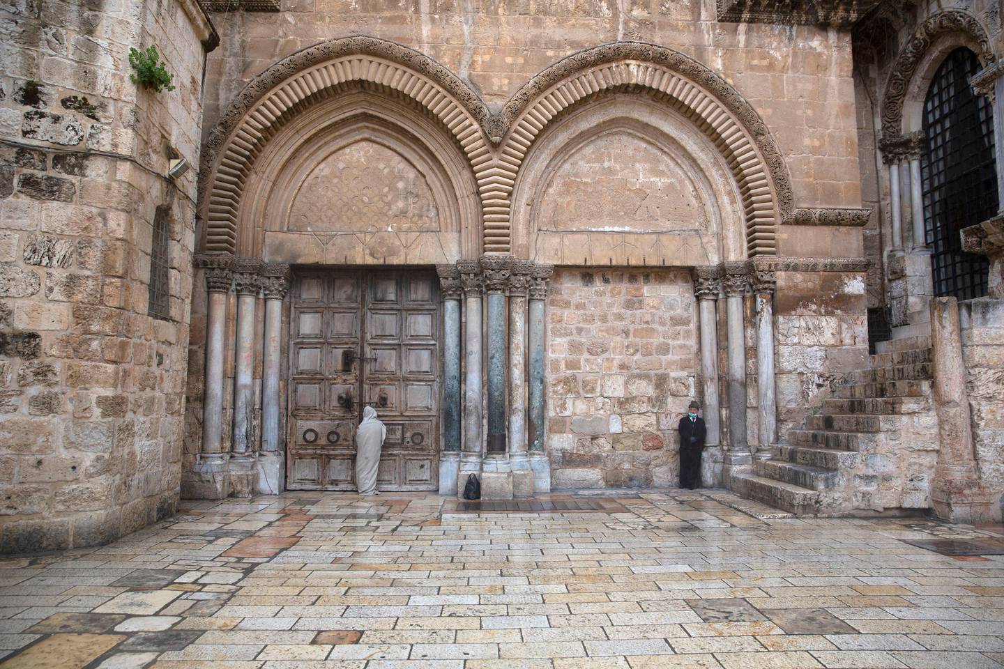 A Christian stands at the closed door of the Church of the Holy Sepulchre, believed by many Christians to be the site of the crucifixion and burial of Jesus Christ, in Jerusalem, Friday, April 10, 2020. Christians are commemorating Jesus' crucifixion without the solemn church services or emotional processions of past years, marking Good Friday in a world locked down by the coronavirus pandemic. (AP Photo/Sebastian Scheiner)
