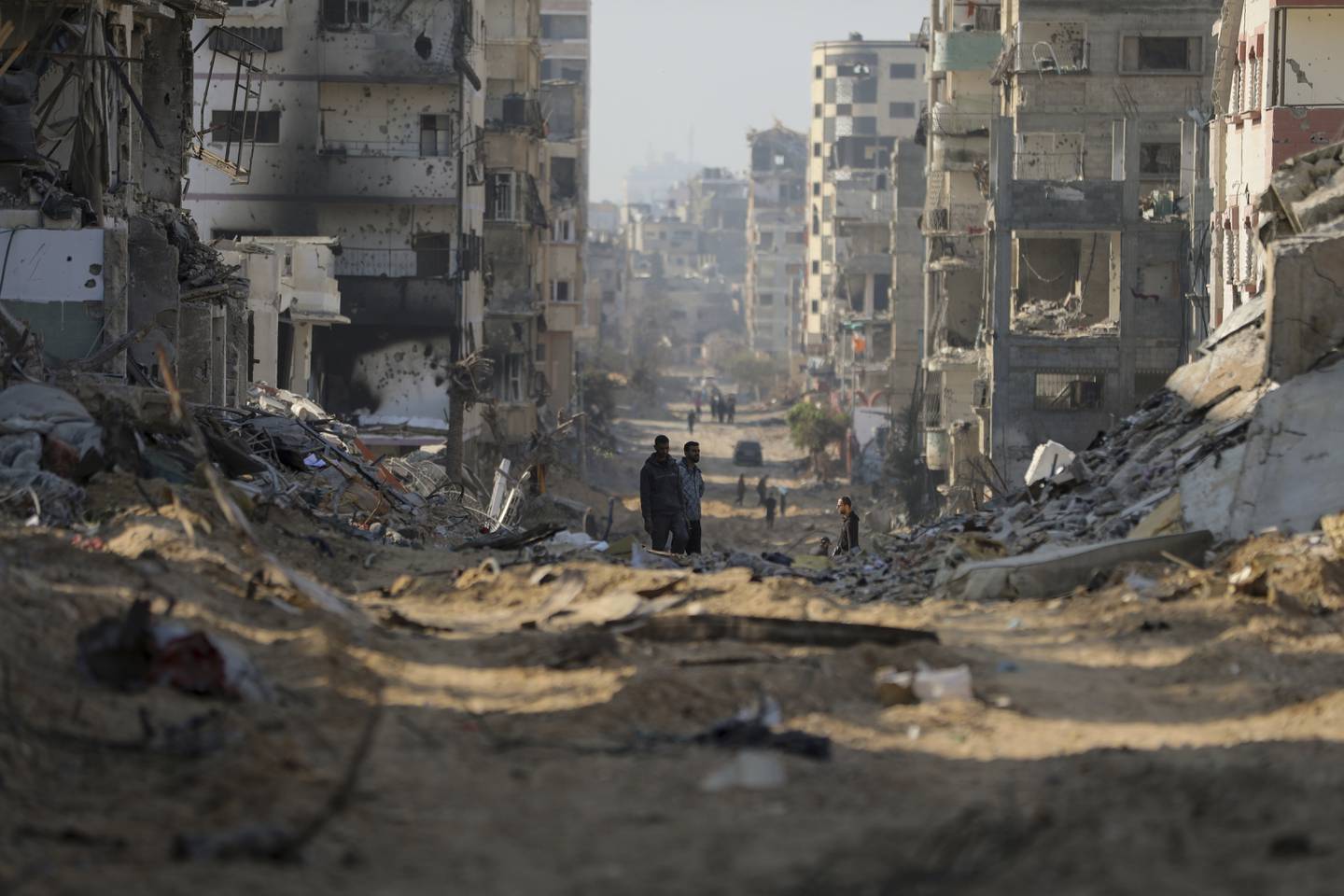 Palestinians walk between the remains of destroyed buildings following the Israeli bombardment on the main road of Gaza City on Tuesday, Jan. 2, 2024. (AP Photo/Mohammed Hajjar)