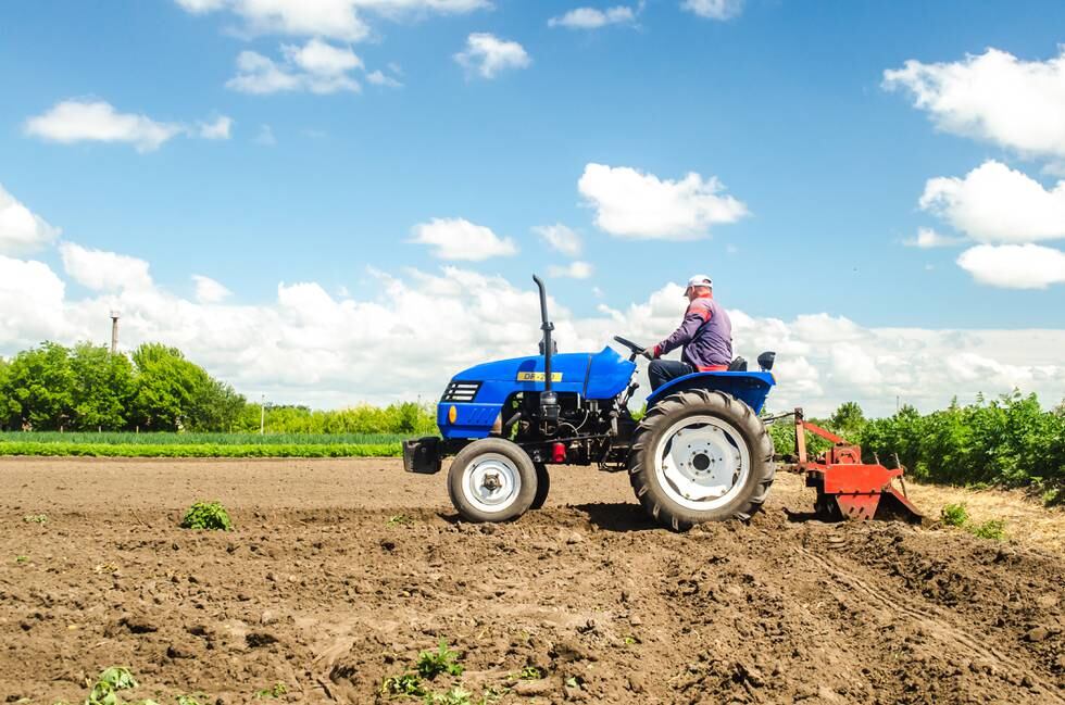 Kherson oblast, Ukraine - May 28, 2020: A farmer on a tractor works in the field and raises dust. Plowing field. Use of agricultural machinery and to simplify and speed up work. Farming, agriculture.