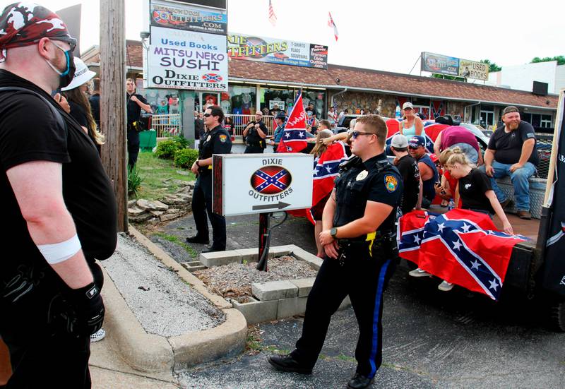 Police stand between Black Lives Matter protesters and counter-protesters during a demonstration in the parking lot by Dixie Outfitters Sunday, June 21, 2020 in Branson, Mo. Protesters have been gathering outside the strip mall store, which specializes in Confederate flags, clothing and other merchandise. The protests have drawn people from opposing sides of the debate  Black Lives Matter demonstrators, as well as those who support the store and the Confederate flag. (Sara Karnes/The Springfield News-Leader via AP)