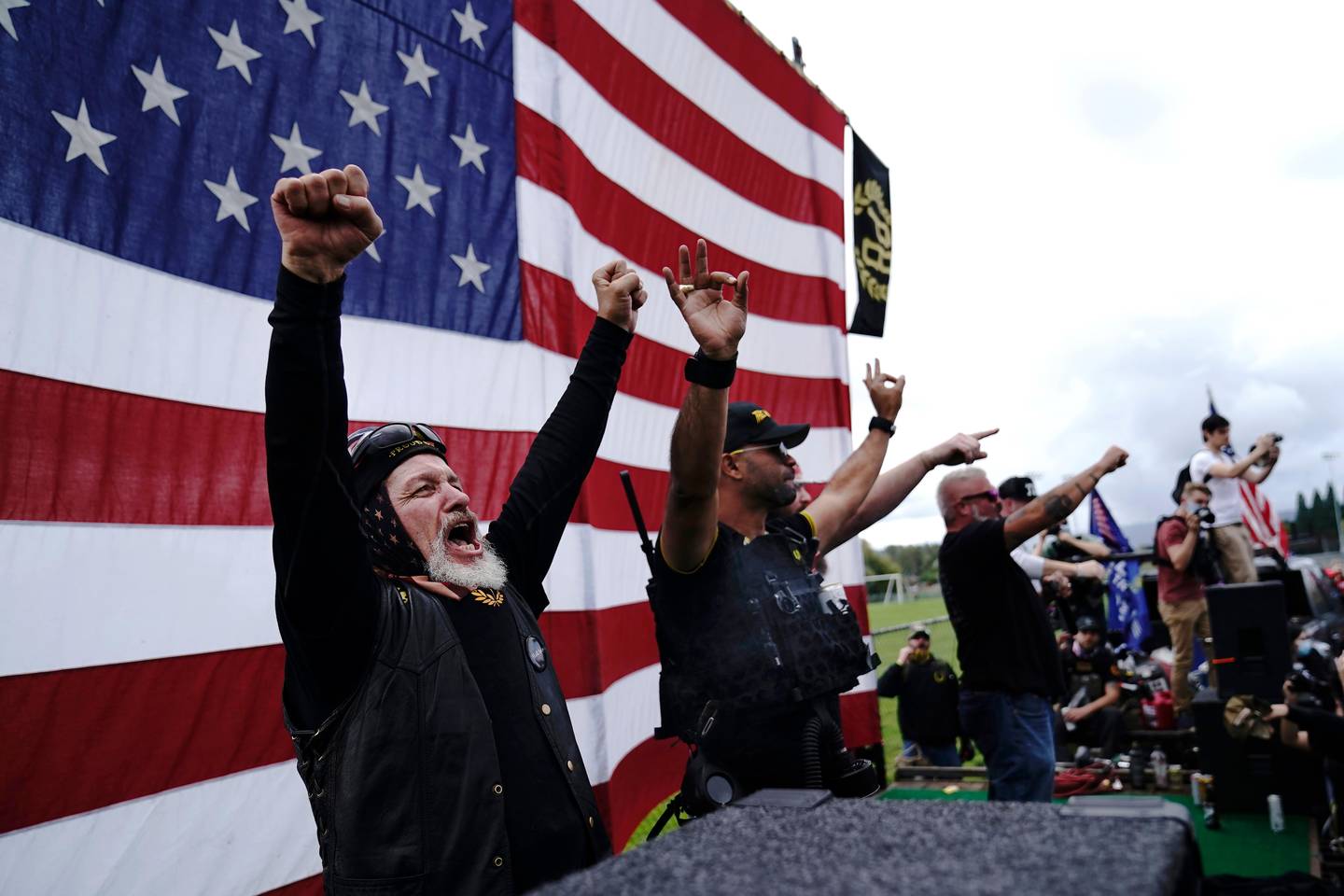 FILE - In this Sept. 26, 2020 file photo, members of the Proud Boys, including leader Enrique Tarrio, second from left, gesture and cheer on stage as they and other right-wing demonstrators rally in Portland, Ore. President Donald Trump didn't condemn white supremacist groups and their role in violence in some American cities this summer. Instead, he said the violence is a left-wing" problem and he told one far-right extremist group to stand back and stand by. His comments Tuesday night were in response to debate moderator Chris Wallace asking if he would condemn white supremacists and militia groups. Trump's exchange with Democrat Joe Biden left the extremist group Proud Boys celebrating what some of its members saw as tacit approval. (AP Photo/John Locher)