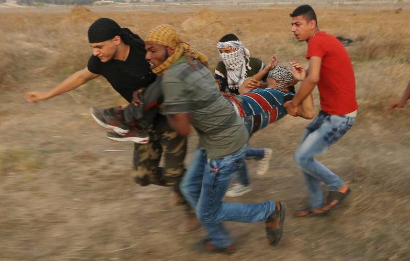 Unge palestinske demonstranter evakuerer en skadet etter sammenstør med israelske tropper nær grensen mellom Israel og Gaza-stripen.