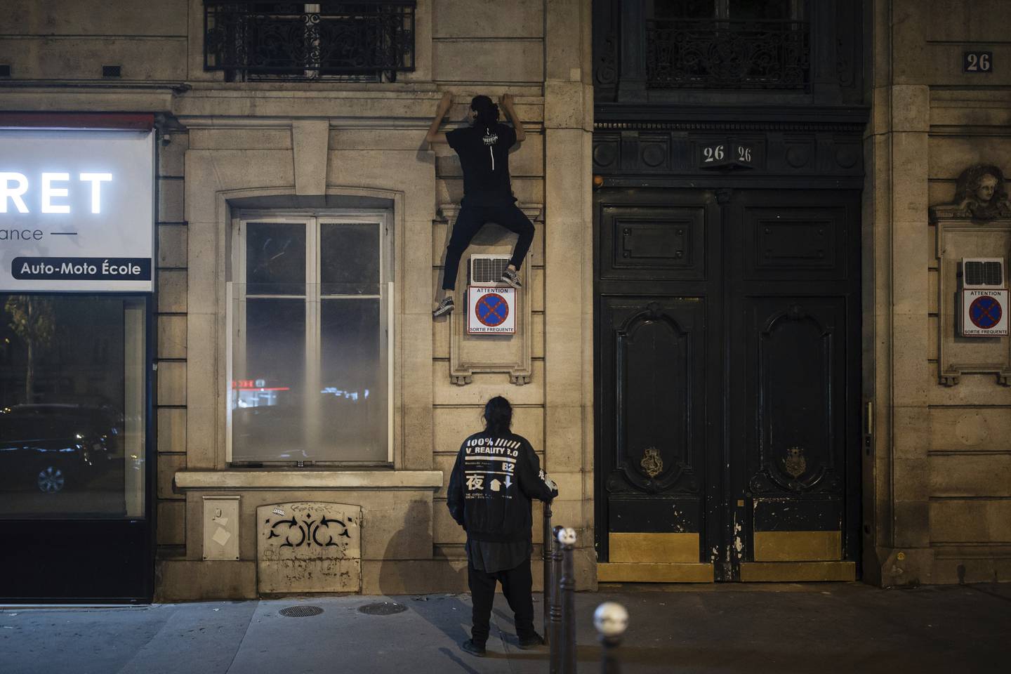 En miljøaktivist fra gruppa On the Spot klatrer opp fasaden på en bygning i Paris for å slå av lyset som står på om natta. Gruppa vil redusere energisløsing og har derfor nattlige tokt der de slår av butikkers lys. Foto: Lewis Joly / AP / NTB