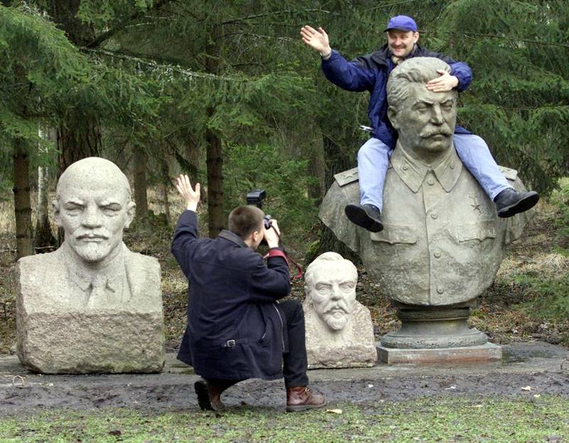 
An unidentified man takes a photo of his friend, who climbed atop a bust of the Soviet dictator Josef Stalin, at Soviet theme park in Grutas, 120 km (75 miles) south of the Lithuanian capital Vilnius, Sunday, April 1, 2001, with busts of the Communist Party and Soviet founder Vladimir Lenin at left and of a Soviet secret police chief Felix Dzerzhinsky at center. Lithuanians laughed and cheered at what they used to be afraid of not long time ago as the Soviet theme park opened Sunday. (AP Photo/Mindaugas Kulbis)