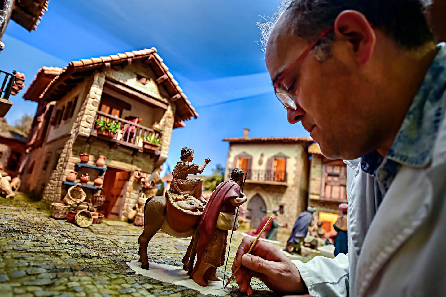 In this photo taken on Friday Nov. 30, 2018, a member of a nativity scene making group, adds the final touches to a nativity scene, known in Spain as ''Belenes'', in Pamplona, northern Spain. Spain celebrates the Christmas season with ancient Catholic traditions including the "Belenes", which are handmade from polystyrene and decorated with small nativity figures. (AP Photo/Alvaro Barrientos)