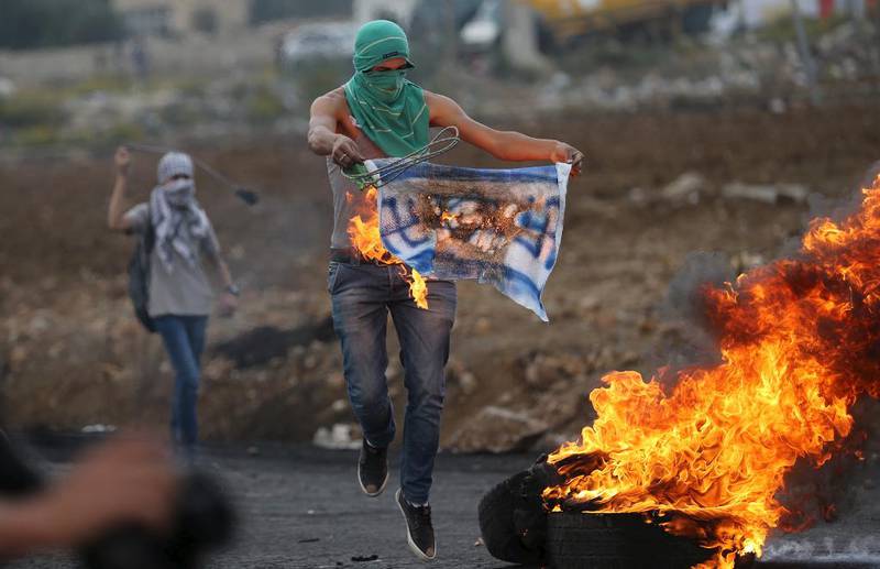 En palestiner i nærheten av den jødiske bosettingen Bet El ved Ramallah på Vestbredden har satt fyr på et slags israelsk flagg påtegnet nazisymboler. 41 palestinere og åtte israelere har mistet livet siden den siste opprørsbølgen startet tidlig i oktober.