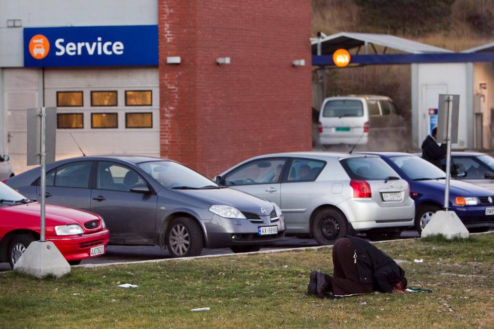 En muslim ber en aftenbønn på gresset ved en bensinstasjon ved Moss. I Norge har religiøs praksis liten plass i den offentlige sfæren. 