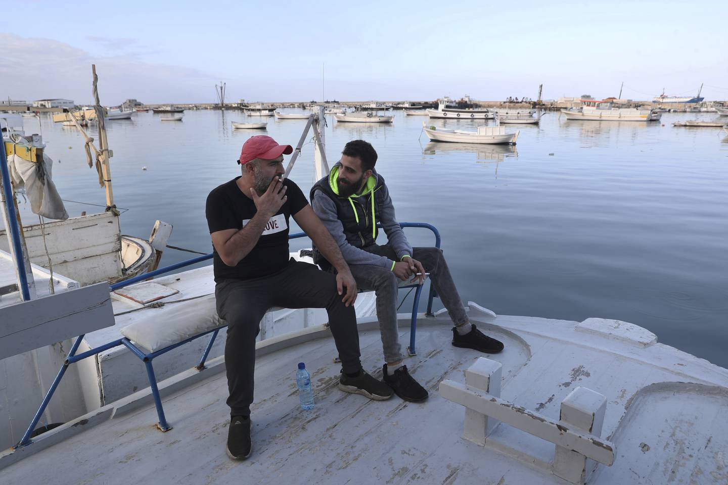 Ziad Khaled Hilweh (til høyre) og vennen Bilal Mousa sitter sammen på en båt langs havnen i Tripoli. I november forsøkte de to å flykte fra landet, men ble fraktet tilbake. Foto: Bilal Hussein / AP / NTB