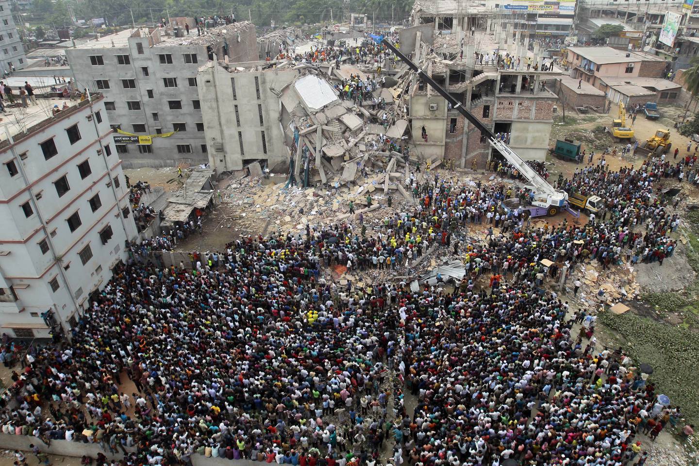 FILE - In this April 25, 2013 file photo, Bangladeshi people gather as rescuers look for survivors and victims at the site of a building that collapsed a day earlier, in Savar, near Dhaka, Bangladesh. A court in Bangladesh's capital accepted murder charges Monday against 41 people including the owner of the Rana Plaza building that collapsed in 2013 and highlighted grim conditions in the country's garment industry.More than 1,100 people, mostly garment factory workers, died when the illegally built complex collapsed in Bangladesh's worst industrial disaster. (AP Photo/A.M.Ahad, File)