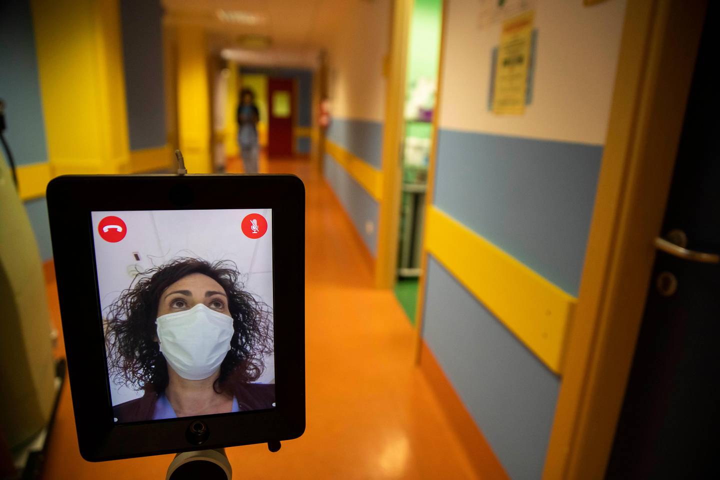 Nurse Helga drives 'Ivo' a tablet supported by a periscopic pole mounted on wheels at 'Ospedale di Circolo' in Varese, Italy, Wednesday, April 8, 2020. Ivo is remotely controlled by the healthcare professional via smartphone. It can enter the rooms and, with a video call system, put the staff in communication with the patients. The new coronavirus causes mild or moderate symptoms for most people, but for some, especially older adults and people with existing health problems, it can cause more severe illness or death. (AP Photo/Luca Bruno)