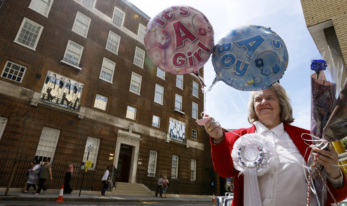 Royal supporter Margaret Tyler displays balloons for the media in front of the Lindo Wing at St Mary's Hospital in London, Monday, July 15, 2013. Britain's Kate, the Duchess of Cambridge plans to give birth to her first child who will be third-in-line to the throne at the hospital in mid-July. While mega-fanfare awaits the gender reveal of the latest British royal, parents-to-be weigh in on finding out the gender of their own little bundle ahead of time. (AP Photo/Kirsty Wigglesworth)