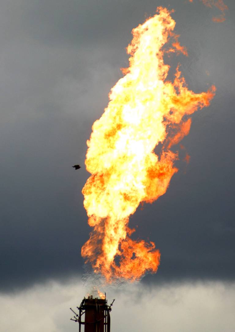 A bird flies by a burning gas flare belonging to Agip oil company in Oshie oil field near the oil rich city of Port Harcourt, Nigeria, Monday, Sept. 20, 2004. A militia group in the Niger Delta will launch