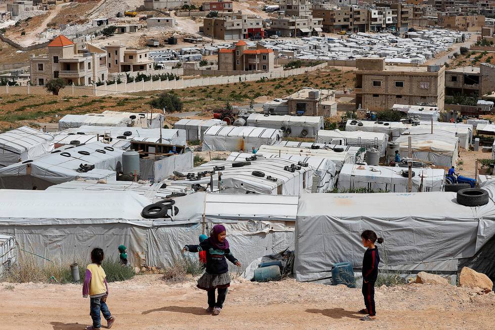 Syrian refugee children play at an informal refugee camp, which is seen set between the houses and buildings in Arsal, near the border with Syria, east Lebanon, Wednesday, June 13, 2018. A public spat between the Lebanese government and the United Nation's refugee agency deepened Wednesday as Lebanon's caretaker foreign minister kept up his criticism, accusing the agency of discouraging Syrian refugees from returning home. Lebanon is home to more than a million Syrian refugees, or about a quarter of the country's population, putting a huge strain on the economy. (AP Photo/Hussein Malla)