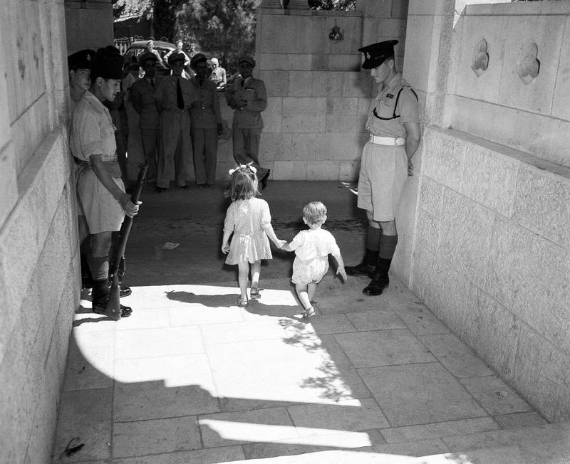To arabiske barn passerer soldater ved YMCA-bygningen i Jerusalem for å få et glimt av FN-delegatene 16. juni 1947. Dette var komiteens første møte i Palestina, der arabiske aktivister arrangerte en heldagsdemonstrasjon i protest mot FNs innblanding.