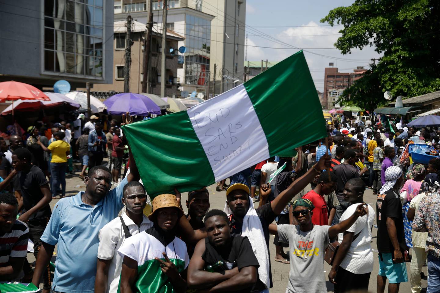 People hold banners as they demonstrate on the street to protest against police brutality, in Lagos, Nigeria, Tuesday Oct. 20, 2020. After 13 days of protests against police brutality, authorities have imposed a 24-hour curfew in Lagos Nigeria's largest city as moves are made to stop growing violence. (AP Photo/Sunday Alamba)