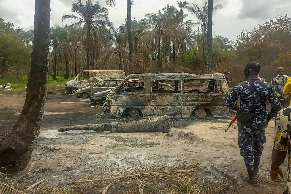 Bildet er av uniformerte soldater som går inn i et område der det står ødelagte biler og trær som har brent. Det er også spor av brann på bakken.  Foto: AP / NTB