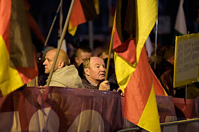 Demonstrators with German flags attend a protest against the visit of German Chancellor Angela Merkel at the East German city Chemnitz on Friday, Nov. 16, 2018. (AP Photo/Jens Meyer)