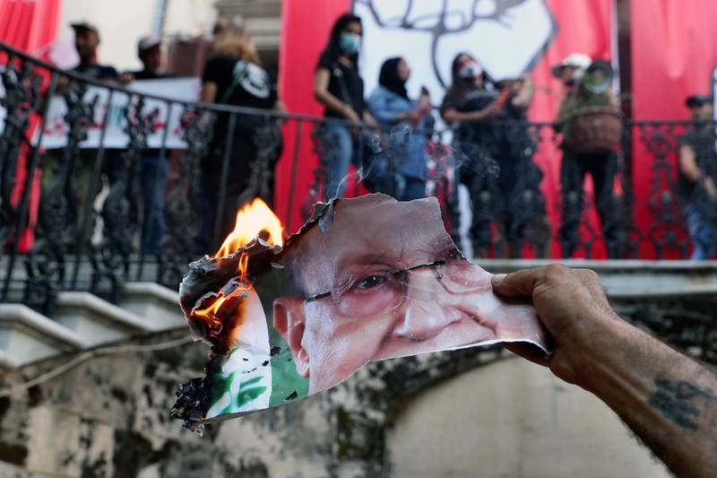 An anti-government protester burns a picture of Lebanese President Michel Aoun inside the Lebanese foreign ministry in Beirut, Lebanon, Saturday, Aug. 8, 2020. A group of protesters, including retired army officers, in Lebanon stormed the building of the foreign ministry during angry rallies in the capital following the destructive Beirut blast earlier this week. (AP Photo/Bilal Hussein)