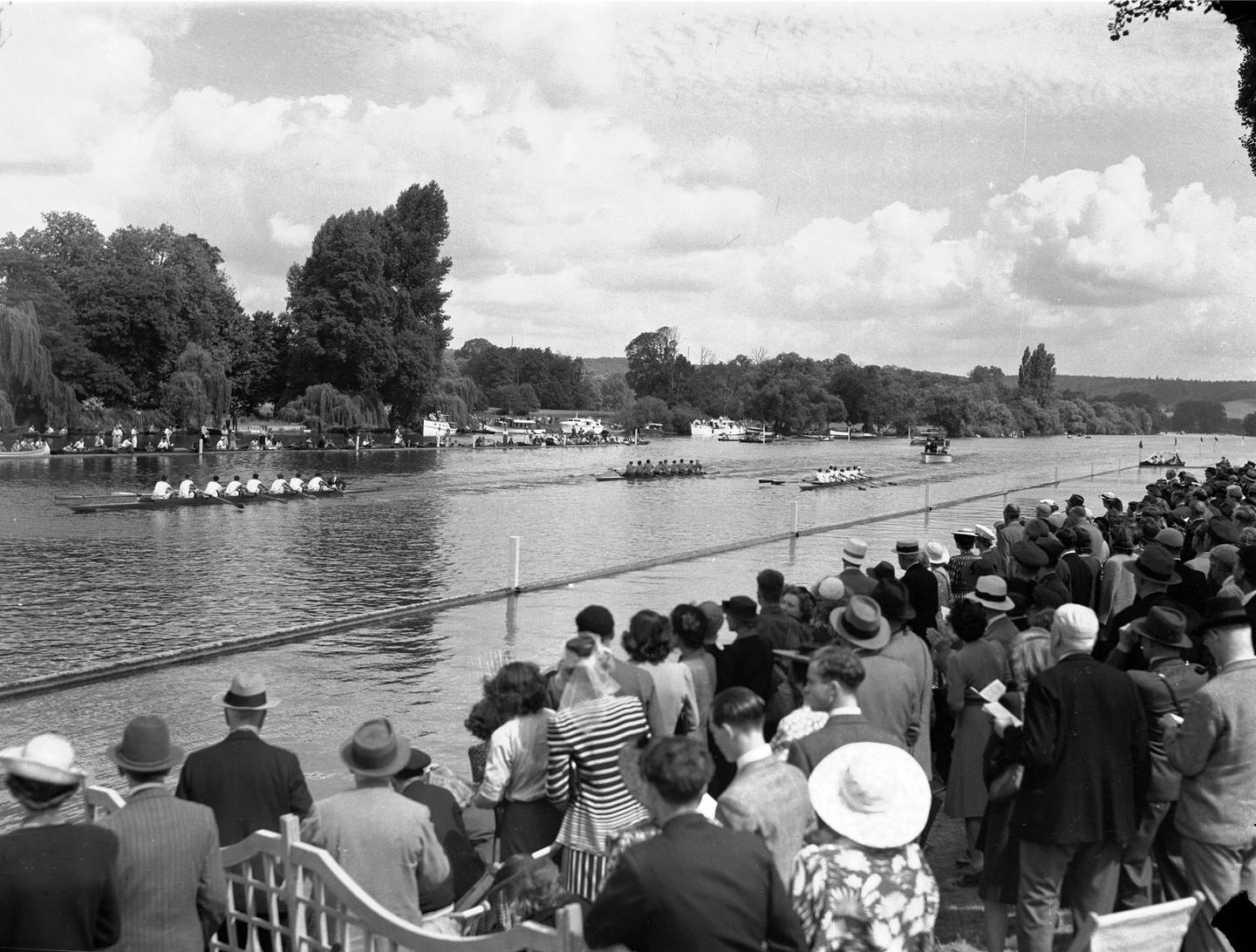 Holiday makers pack the bank of the River Thames during the Henley Regatta, Oxon., England, the first time it has been held since 1939, on July 7, 1945. The Magdalen College, Oxford, crew, left, pull away from Christ's College, Cambridge and the Royal Australian Air Force crews during the regatta. (AP Photo/Stf/Priest)