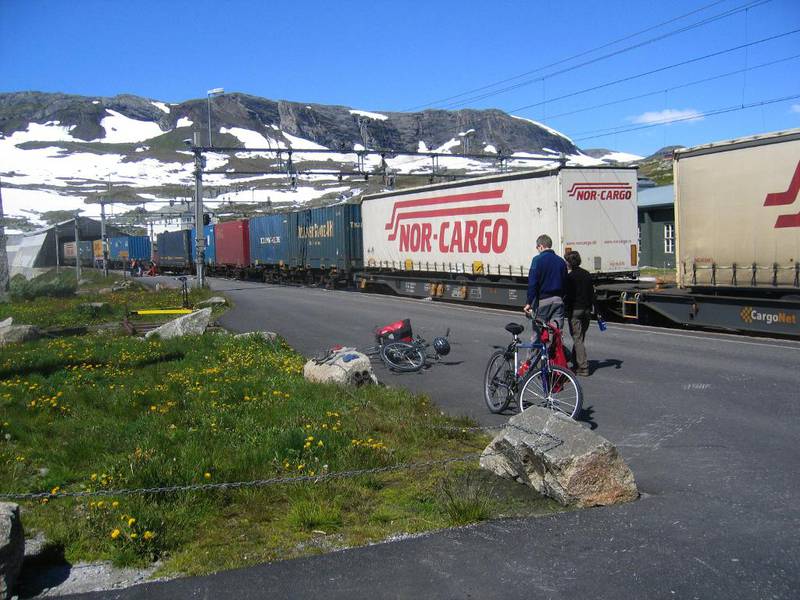 Containertogene går jevnt og trutt på Bergensbanen forbi Finse,  hvor turistene koser seg i finværet. 