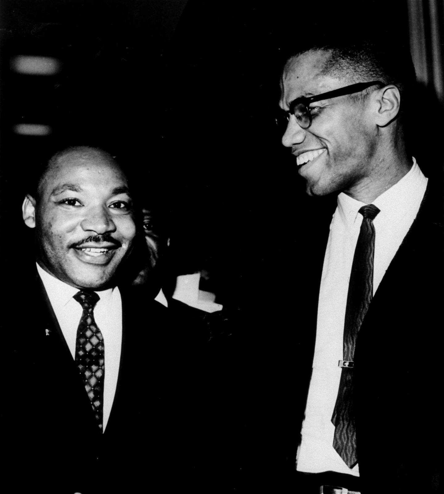 The Rev. Martin Luther King, Jr., left, of the Southern Christian Leadership Conference, and Malcolm X, head of a new group known as Muslim Mosque, Inc., smile for photographers March 26, 1964, at the Capitol.  They shook hands after King announced plans for  