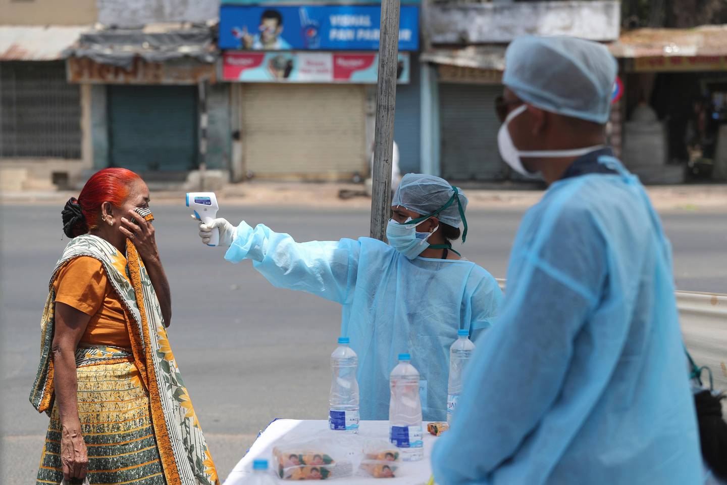 An Indian health worker checks the temperature of a woman during lockdown to prevent the spread of new coronavirus in Ahmedabad, India, Wednesday, April 8, 2020. The new coronavirus causes mild or moderate symptoms for most people, but for some, especially older adults and people with existing health problems, it can cause more severe illness or death. (AP Photo/Ajit Solanki)