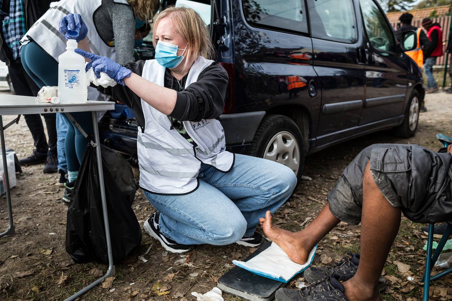 25.	Noleen, en britisk doktor og feltkoordinator for F.A.S.T. – First Aid Support Team i Calais, behandler skader på foten til en ung sudanesisk gutt i nærheten av Old Lidl, den største teltleiren i byen.