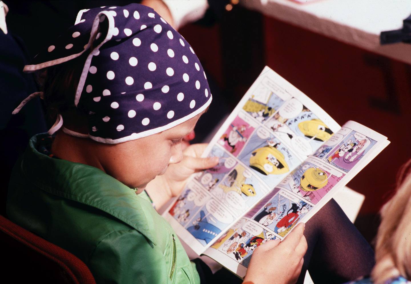Kongsberg 19770904: Prinsesse Märtha Louise - i blått skaut med prikker - fotografert på Donald Duck-lekene i 1977. Her leser prinsessen et Donald Duck blad . 
NTB arkivfoto: Nils Maudal / SCANPIX