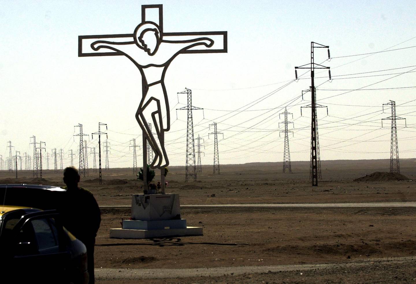 A statue of Christ appears between various energy towers in the middle of the Atacama desert in Mejillones near Antofagasta, Chile, Thursdasy, April 29, 2004. The towers belong to Edelnor, a regional power company, which has been affected by the cuts in the supplies of gas to Chile by Argentina. (AP Photo/Santiago Llanquin)
