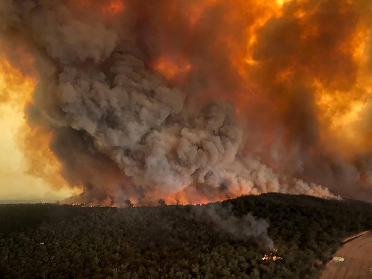 FILE - In this Monday, Dec. 30, 2019, aerial file photo, wildfires rage under plumes of smoke in Bairnsdale, Australia. U.S. officials said Tuesday, Jan. 7, 2020 they planning to send at least 100 more firefighters to Australia to join 159 already there battling blazes that have killed multiple people and destroyed thousands of homes. (Glen Morey via AP, File)