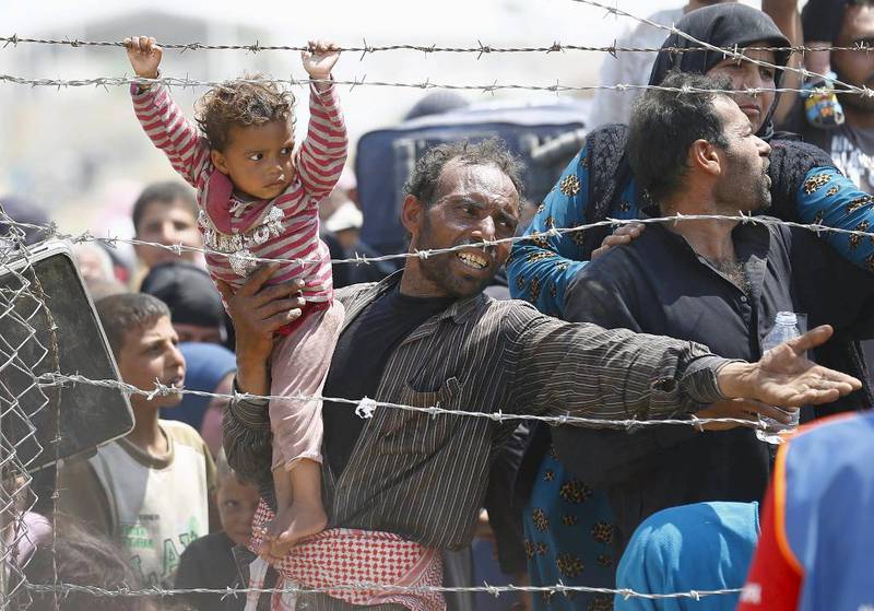 En fortvilet syrisk flyktning holder fast på datteren mens han ber om å få krysse grensen inn til Tyrkia ved grensestedet Akcakale for to uker siden. Disse flyktningene dro i hui og hast fra byen Tel Abiad fordi de ventet kamper mellom Den islamske staten (IS) og kurdiske styrker. 