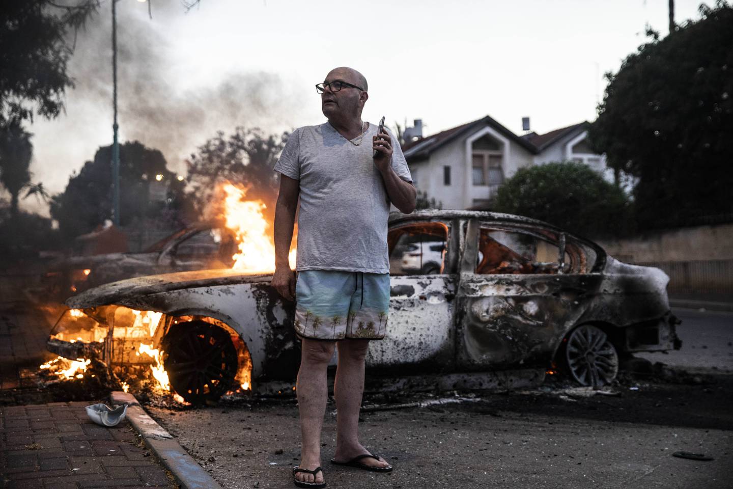 Jacob Simona står ved siden av sin brennende bil. Den ble satt fyr på under opptøyer mellom israelske arabere og jøder i byen Lod 11. mai. Foto: AP Photo