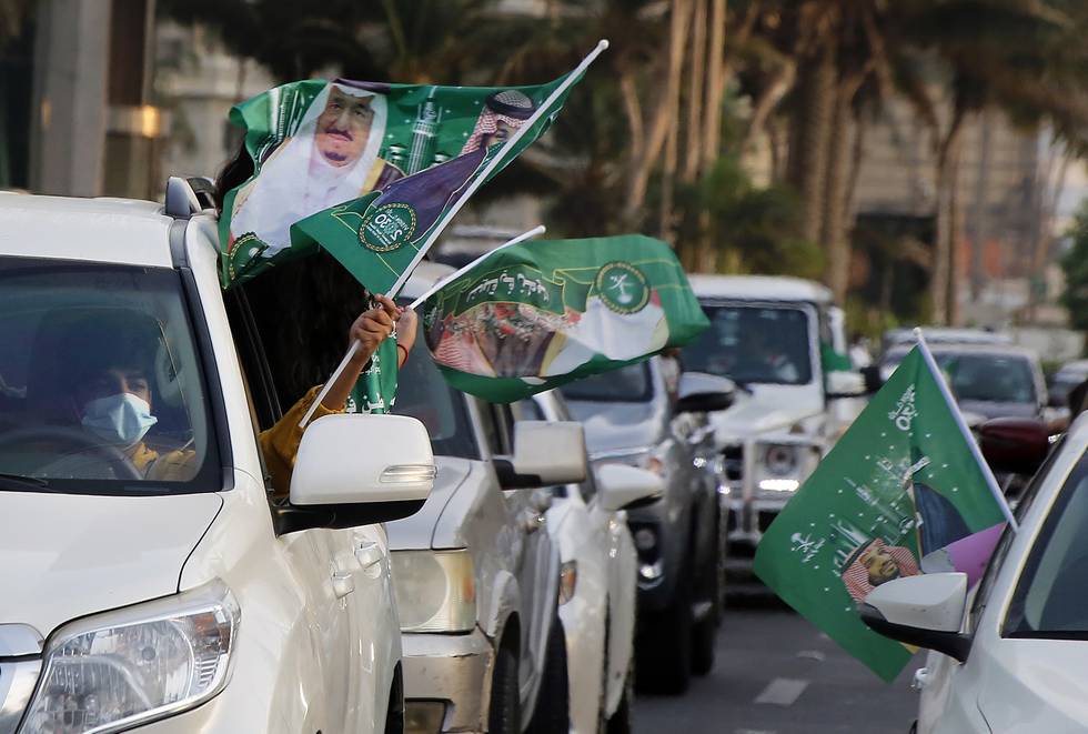 Saudis wave national flags with pictures of Saudi King Salman, right, and Crown Prince Mohammed bin Salman during celebrations marking National Day to commemorate the unification of the country as the Kingdom of Saudi Arabia, in Jiddah, Saudi Arabia, Wednesday, Sept. 23, 2020. (AP Photo/Amr Nabil)