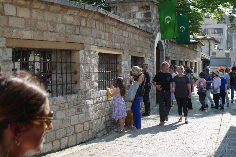 Ei kvinne tek ein pause på handleturen for å be utanfor Gazi Husrev-beg moskeen i Sarajevo.